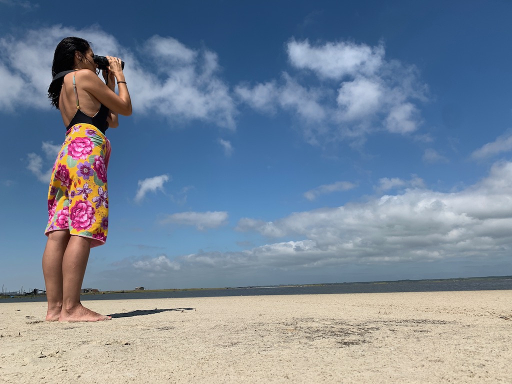 mulher na beira da lagoa olhando para o céu com binóculos