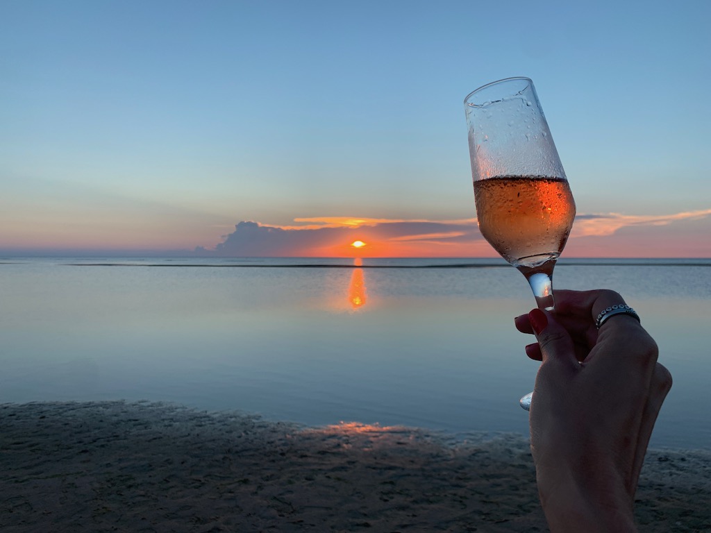vista do pôr do sol com mão segurando taça de espumante