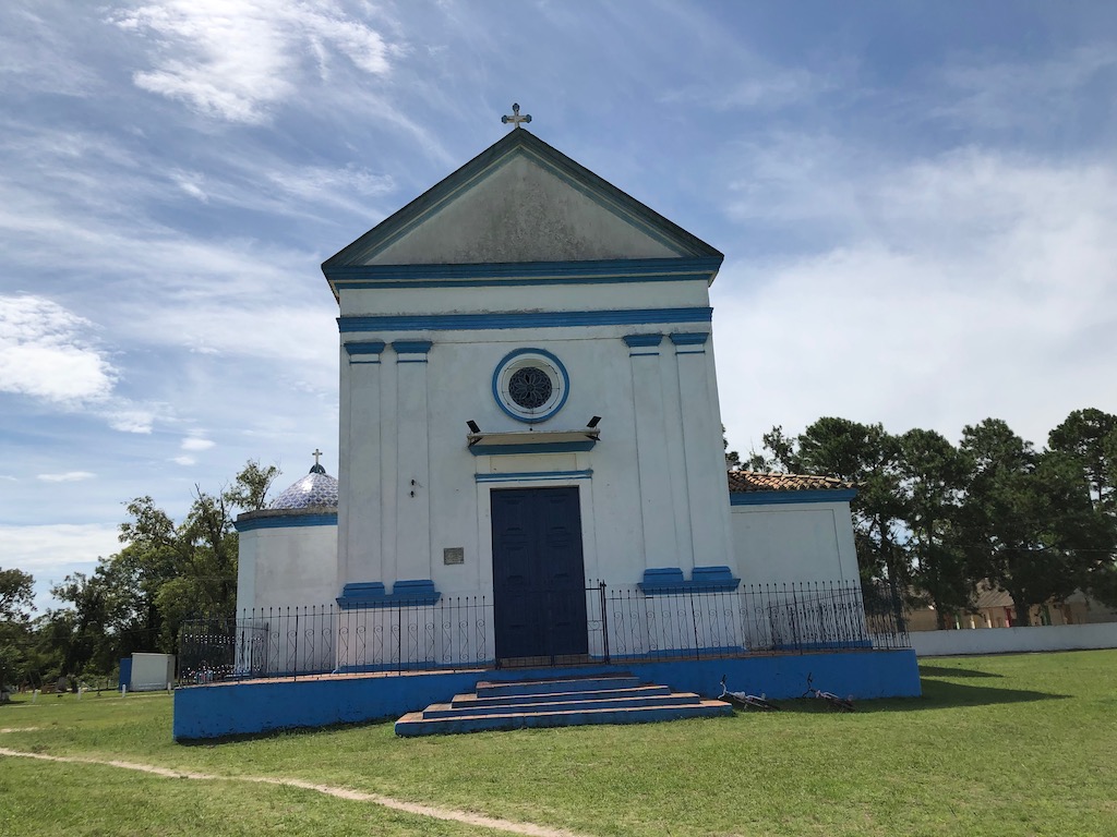 igreja de Santa Isabel, nas cores azul e branco, com céu azulado e grama verdinha
