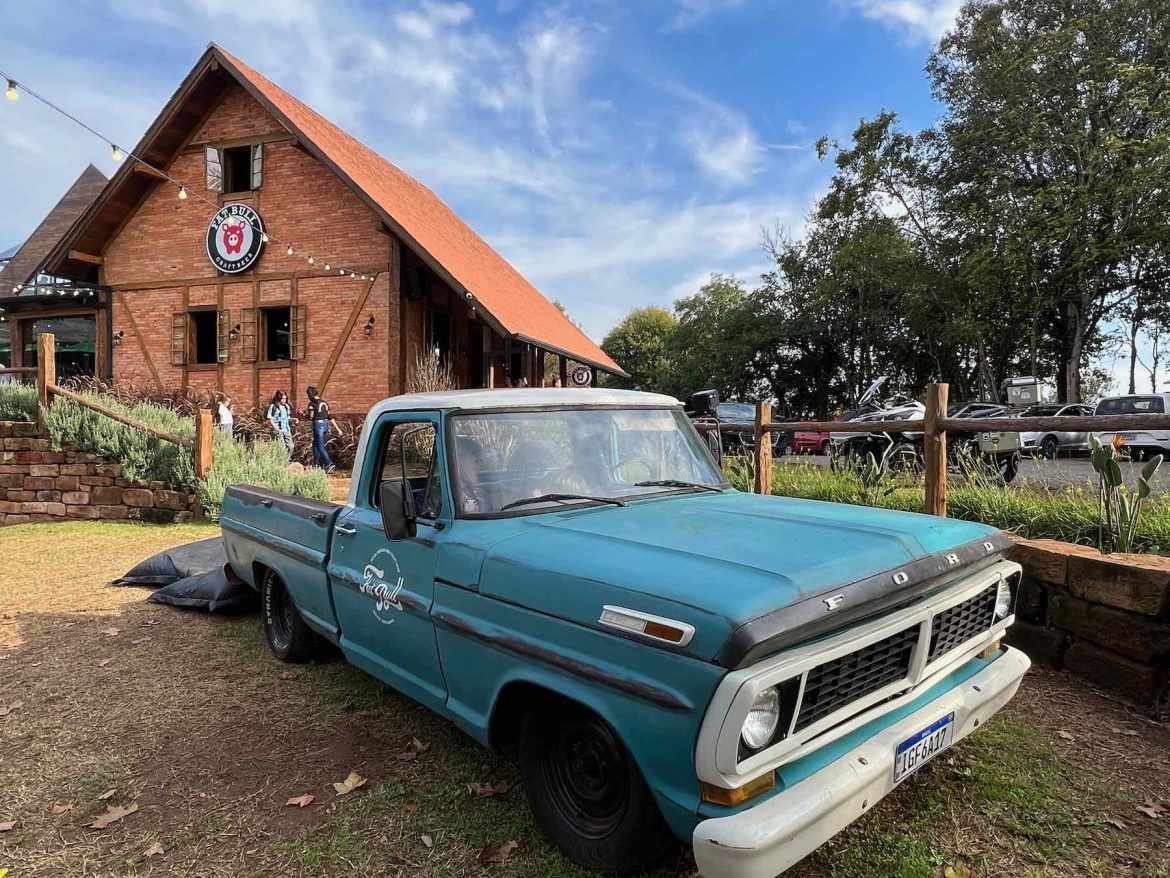 Pickup azul com casarão do Rancho Fat Bull no fundo.