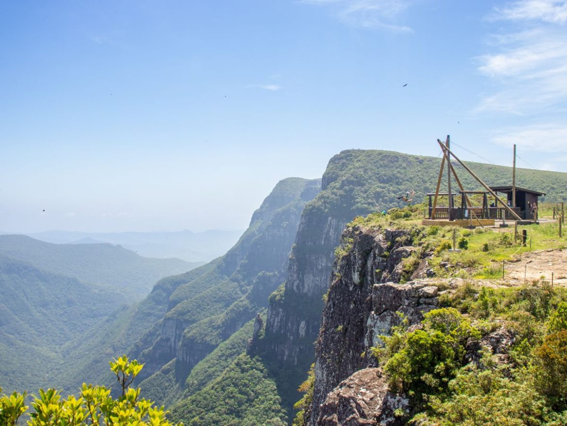 Na foto o Cânion Fortaleza aparece com uma distância mais longa, mostrando seus paredões verdes e o céu azul
